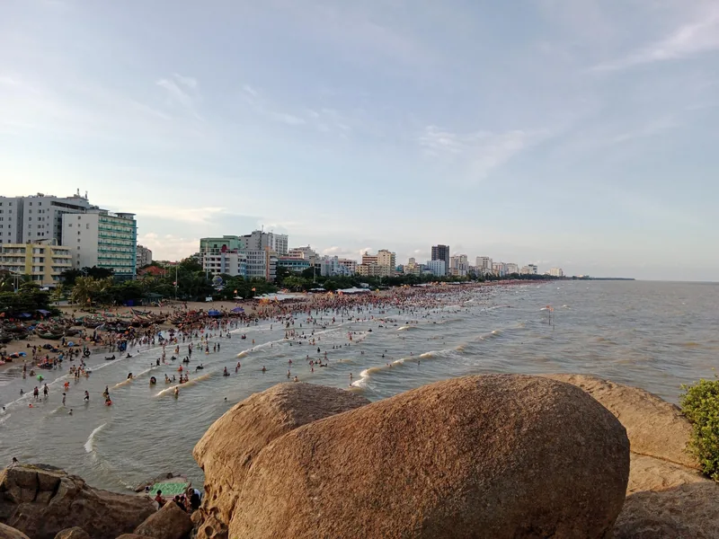 Du khách tắm biển đông đúc tại bãi biển Sầm Sơn, nhìn từ tảng đá lớn hướng ra dãy khách sạn ven biển.