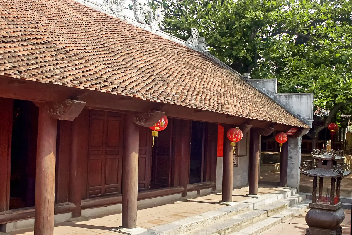 Một ngôi đền truyền thống với mái ngói cong và đèn lồng đỏ treo trên các cột gỗ gần Pù Luông.