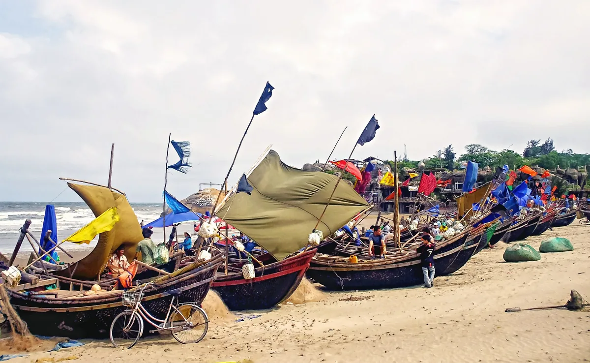 Những thuyền gỗ đánh cá với cánh buồm và lá cờ sặc sỡ đậu trên bãi biển Sầm Sơn, Thanh Hóa.